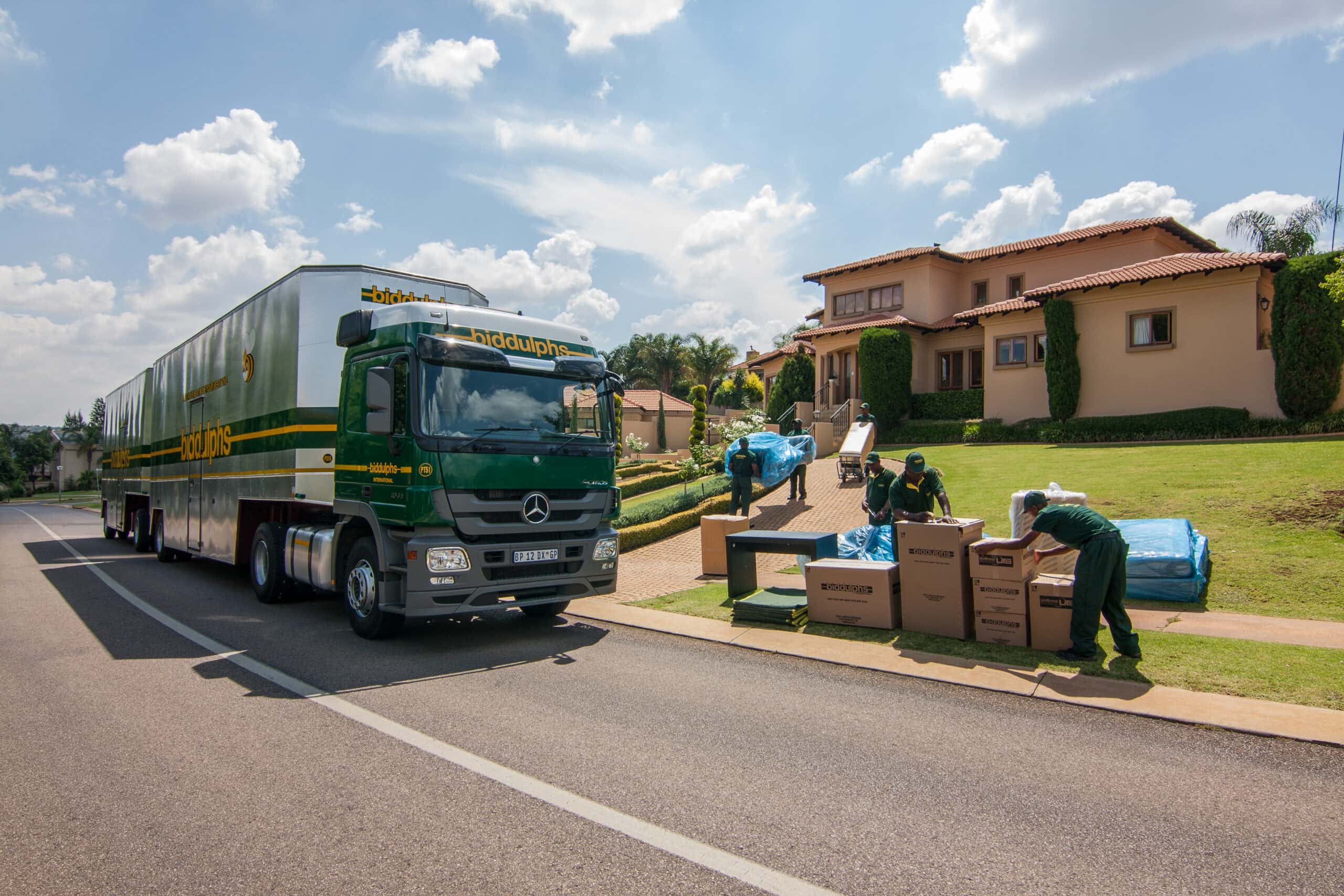 A Biddulphs removal truck outside a family home while the crew wraps furniture