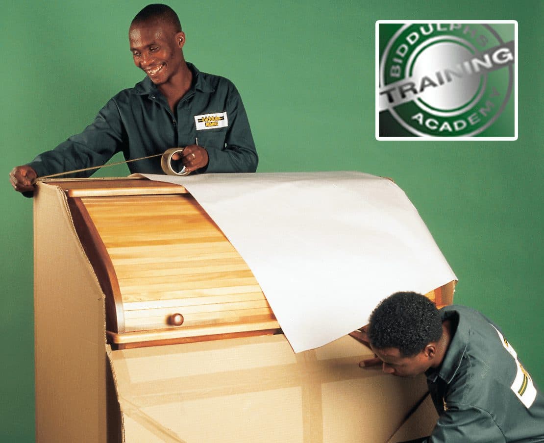 A Biddulphs packer wrapping a wooden cabinet in paper